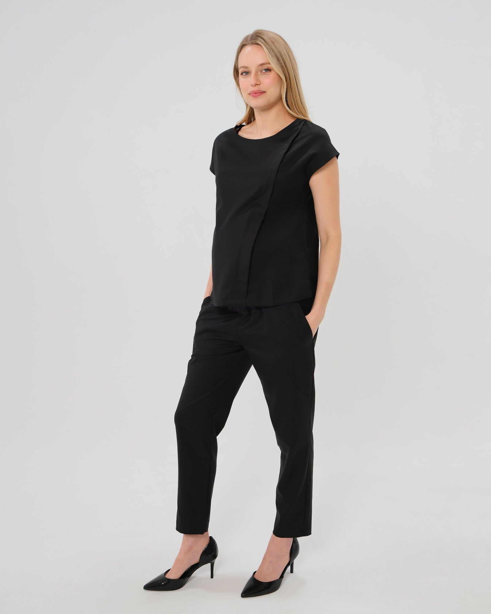 Black maternity work pants, under belly style, cut in all-season wool blend with hidden flexible waist adjustment, deep pockets, and stylish straight leg. Maternity trousers cropped for tall mamas and full length for petite pregnant women. Postpartum friendly women's wear for business, wedding guest, dinner, and occasion.