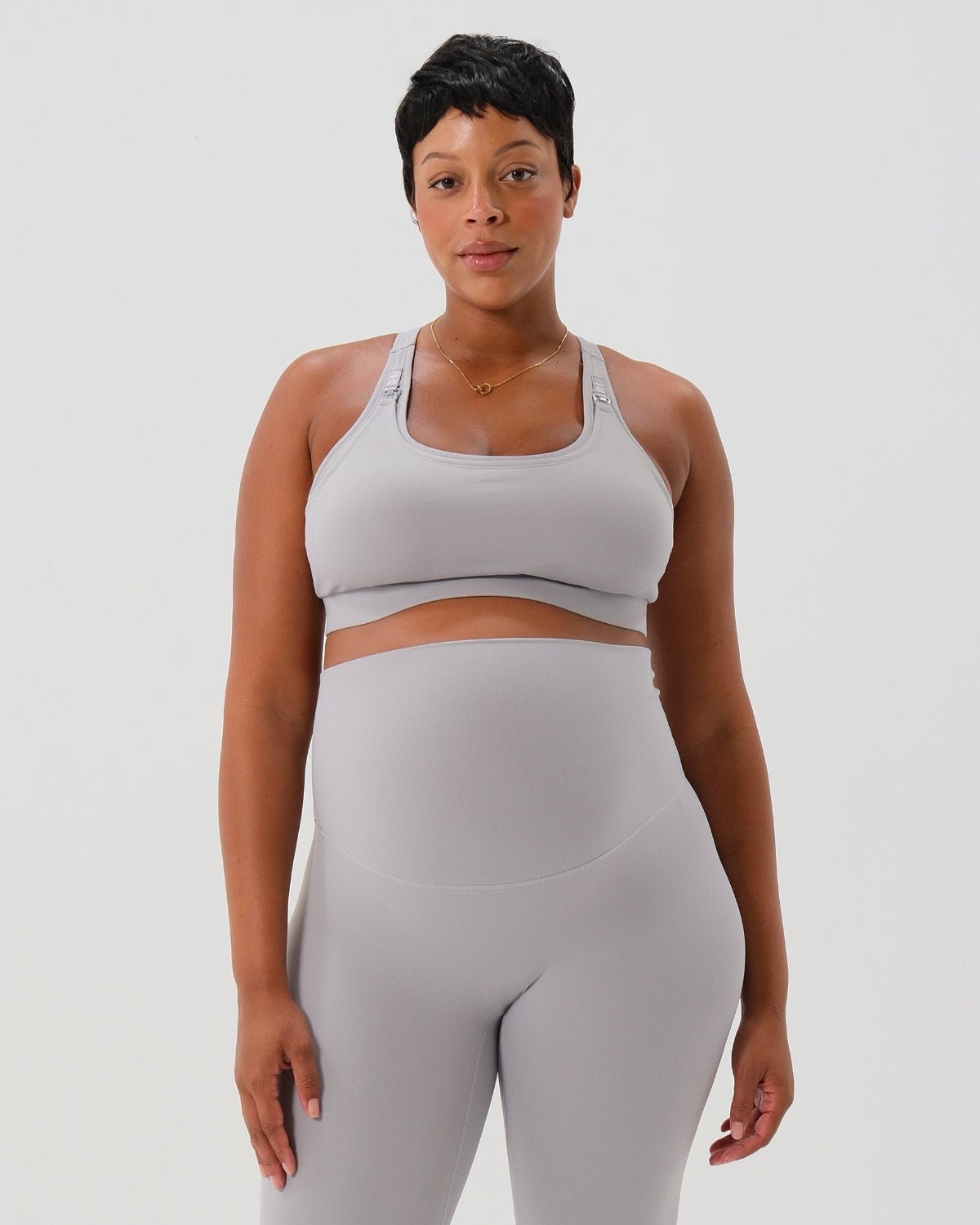 Light gray one-shoulder maternity and nursing sports bra and matching leggings. The bra features one-handed clip access for easy breastfeeding. Premium maternity activewear by AXK is offered in petite and plus size.