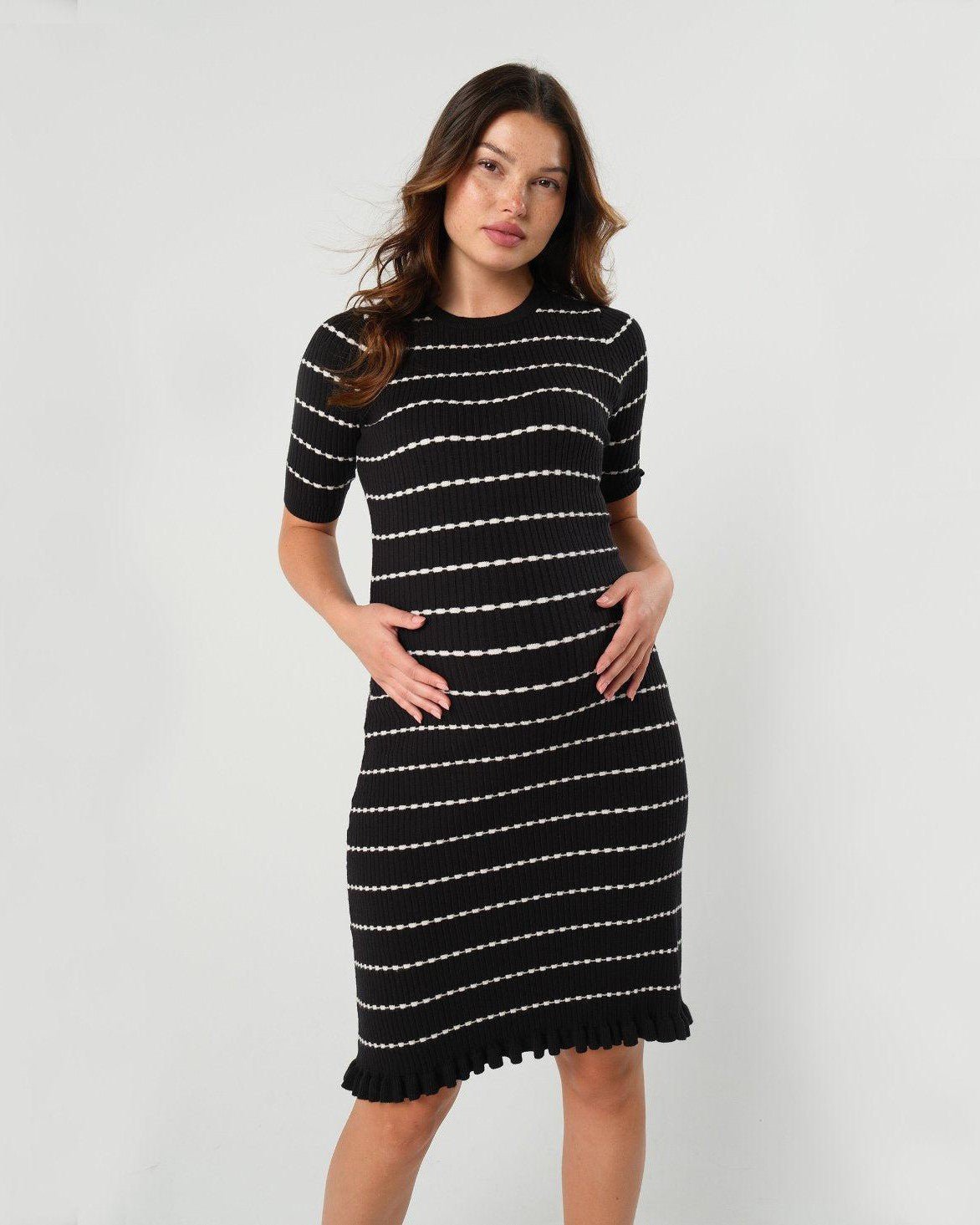 Striped knit maternity and nursing dress in black and white. This knee length dress features three-quarter length sleeves with a feminine hem detail. Ideal for maternity business workwear, date night, church, a wedding guest outfit, brunch, and occasion. Petite and tall friendly. MARION offers the best luxury maternity workwear and fashion on the market.