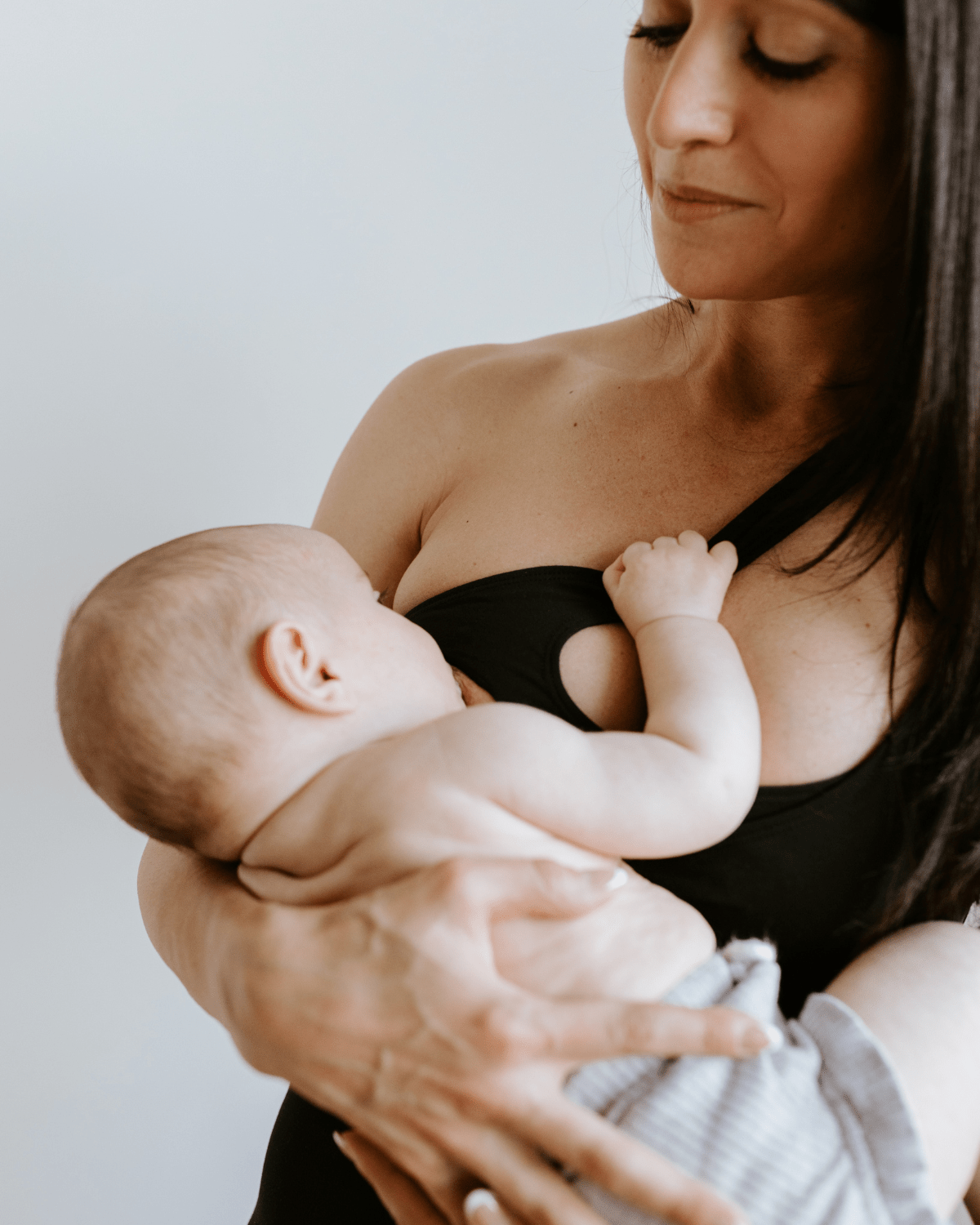 Black one-shoulder maternity and nursing sports bra and athleisure top. Luxe nylon fabric with one hand breastfeeding release clips. 