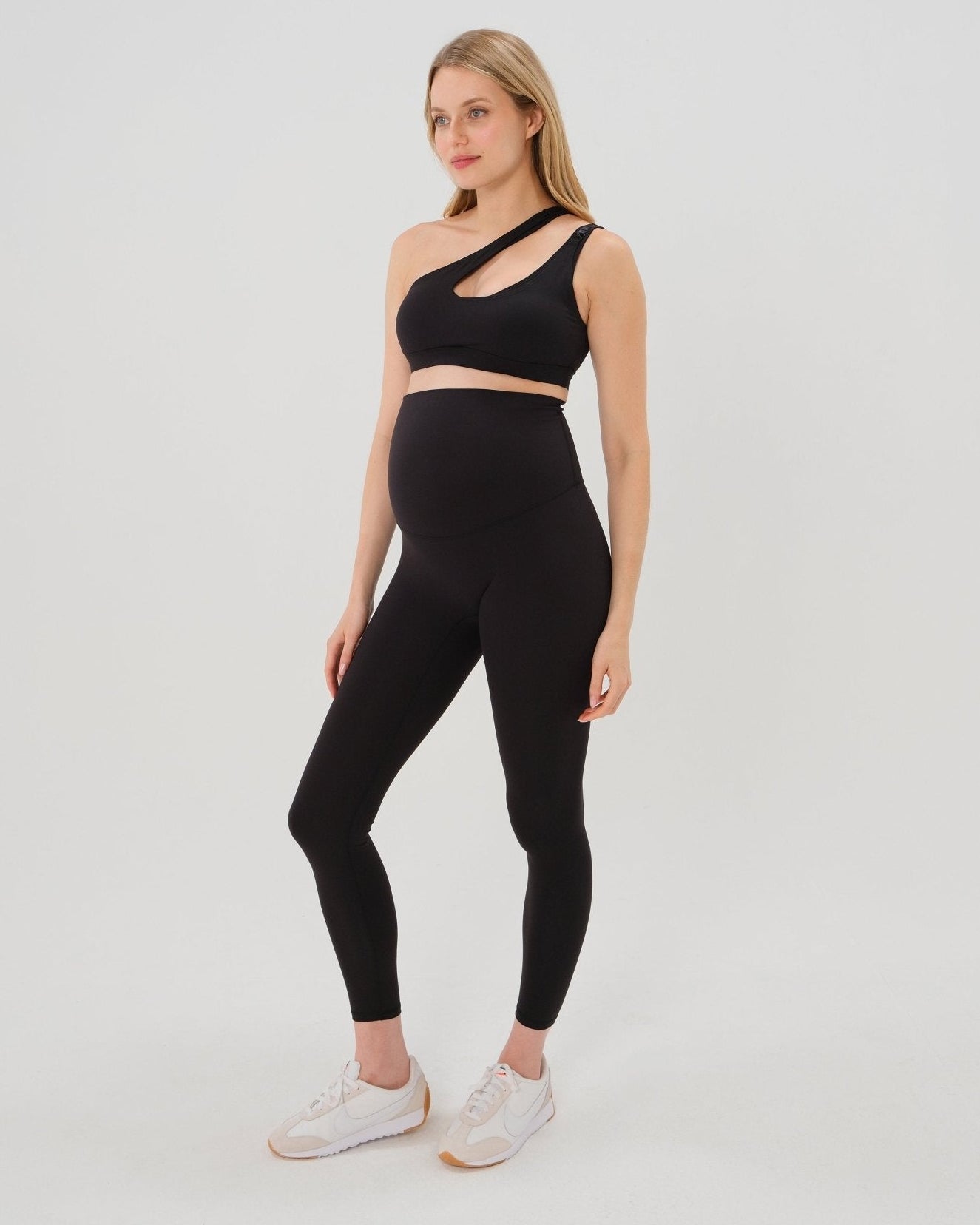 Pregnant woman wearing premium black AXK maternity leggings with flattering scrunch butt and matching high-impact, racerback nursing sports bra. Best reviewed high quality maternity athletic and activewear for 2026, perfect for running, pregnancy yoga, walking, and loungewear. Available in standard and plus sizes, petite and tall friendly. 