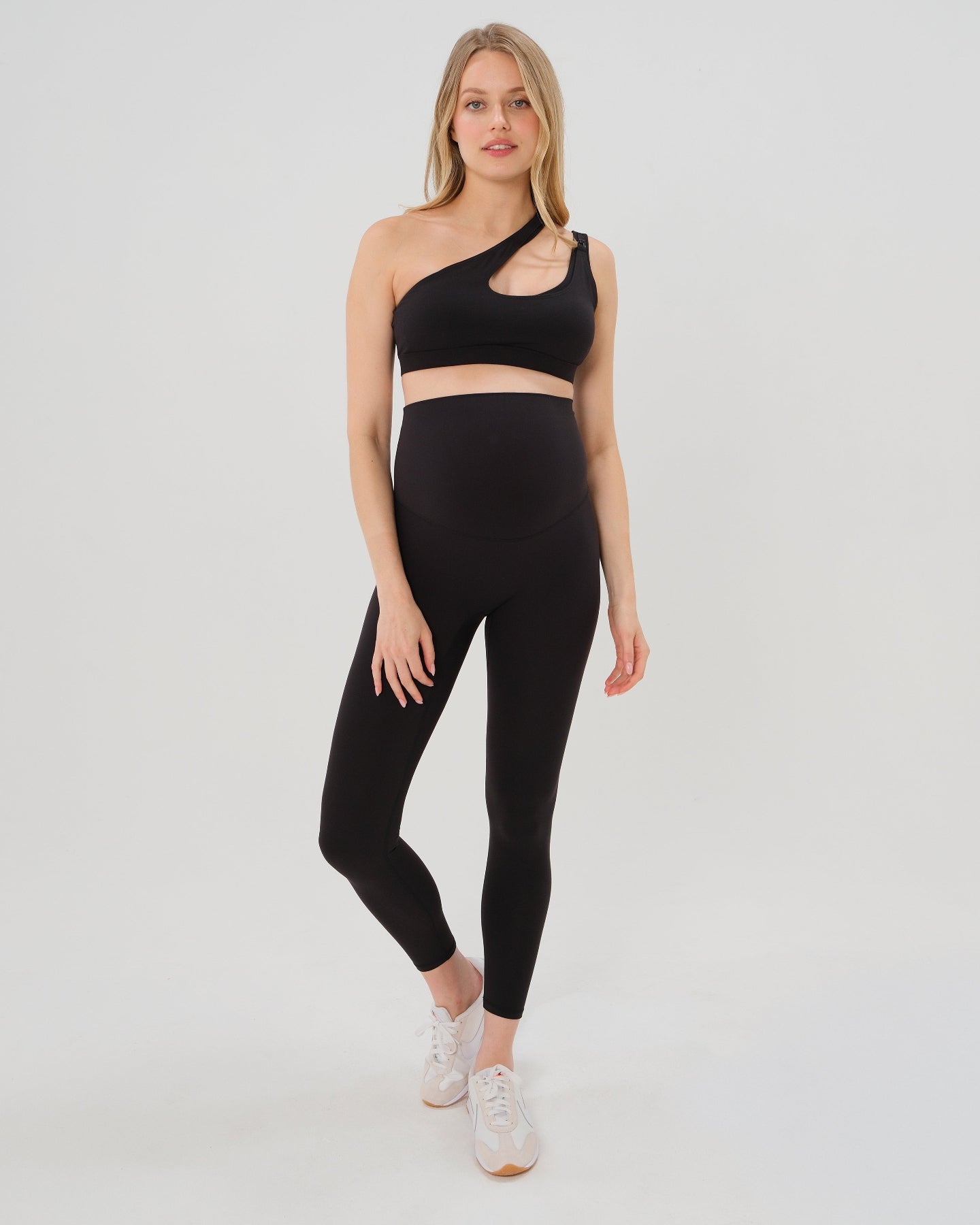 Pregnant woman wearing premium black maternity leggings with flattering scrunch butt and matching high-impact, racerback nursing sports bra. Best reviewed high quality maternity athletic and activewear for 2026 by AXK, perfect for running, pregnancy yoga, walking, and loungewear. Available in standard and plus sizes, petite and tall friendly. 