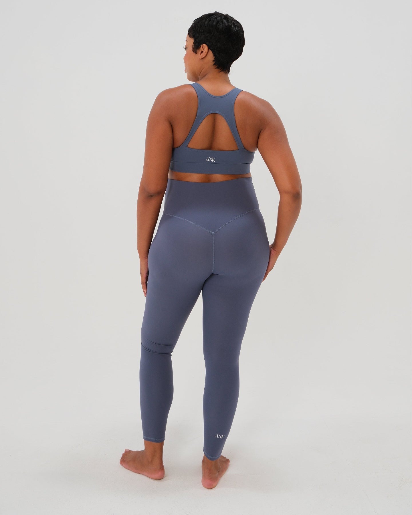 Pregnant plus size model wearing premium blue AXK maternity leggings with a supportive high waist, bum flattering back v seam, seamless front design, and butter soft stretch fabric. Best selling with glowing 5-star reviews, these leggings are perfect for running, pregnancy yoga, walking, biking, or loungewear. High quality 2026 maternity athletic and activewear in regular and plus sizes. Petite and tall friendly. 