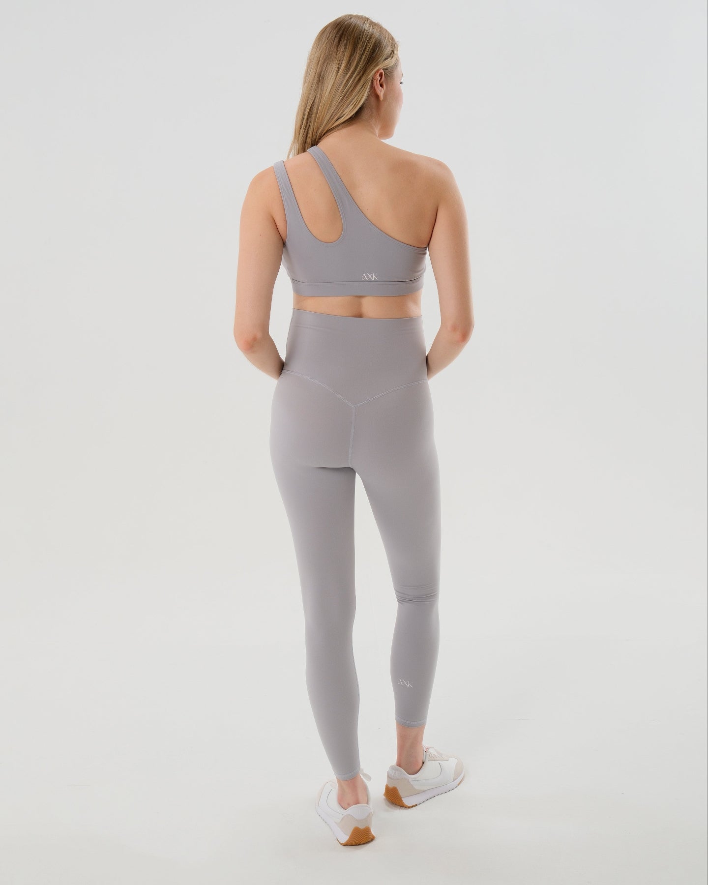 Pregnant model wearing premium light gray AXK maternity leggings with a supportive high waist, bum flattering back v seam, seamless front design, and butter soft stretch fabric. Best selling with glowing 5-star reviews, these leggings are perfect for running, pregnancy yoga, walking, biking, or loungewear. High quality 2026 maternity athletic and activewear in regular and plus sizes. Petite and tall friendly. 