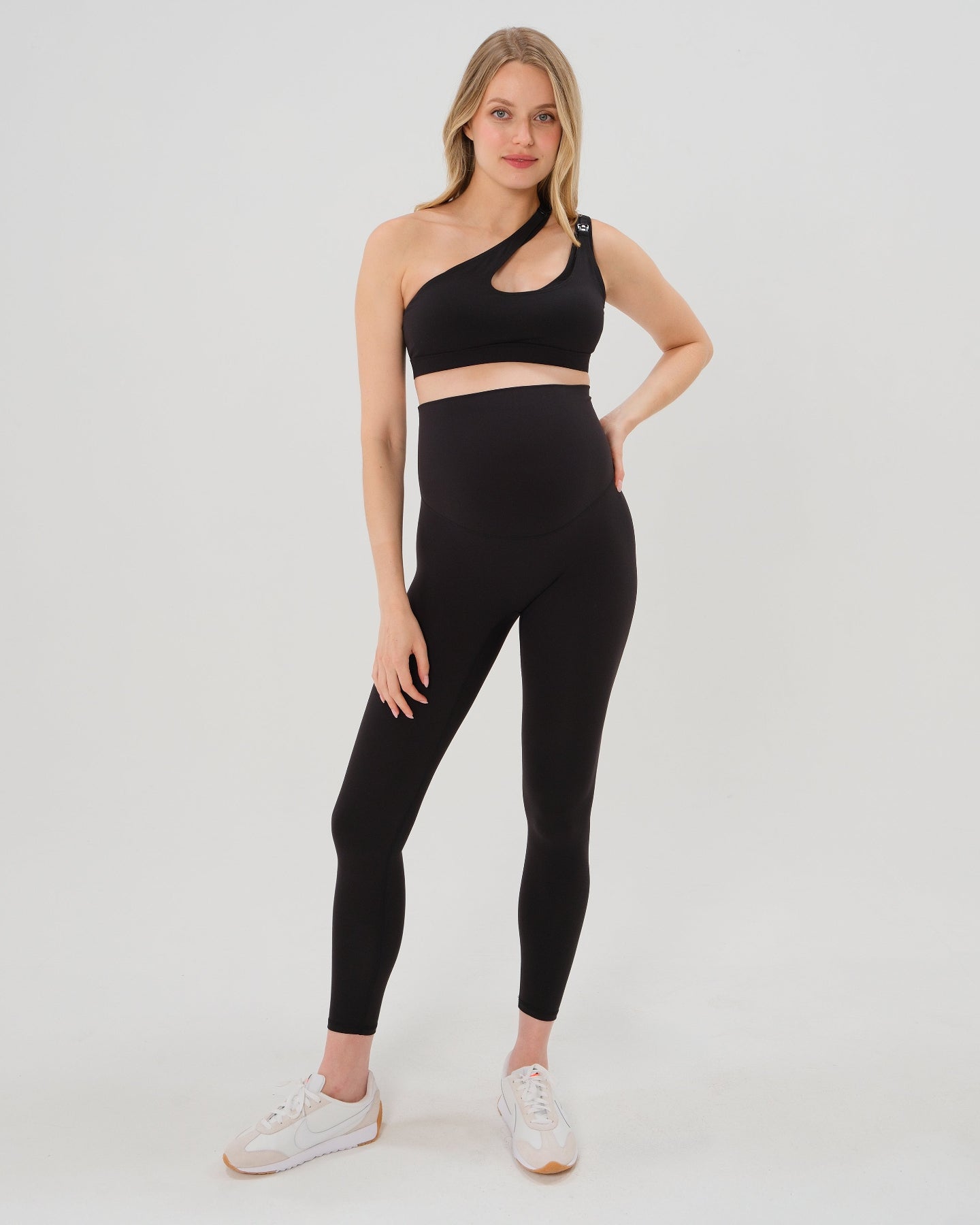 Pregnant model wearing premium black AXK maternity leggings with a supportive high waist, bum flattering back v seam, seamless front design, and butter soft stretch fabric. Best selling with glowing 5-star reviews, these leggings are perfect for running, pregnancy yoga, walking, biking, or loungewear. High quality 2026 maternity athletic and activewear in regular and plus sizes. Petite and tall friendly. 