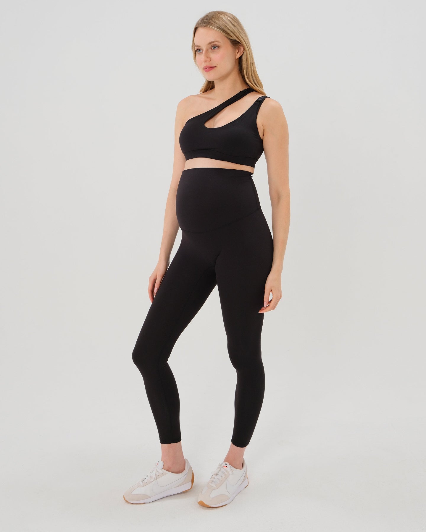 Pregnant model wearing premium black AXK maternity leggings with a supportive high waist, bum flattering back v seam, seamless front design, and butter soft stretch fabric. Best selling with glowing 5-star reviews, these leggings are perfect for running, pregnancy yoga, walking, biking, or loungewear. High quality 2026 maternity athletic and activewear in regular and plus sizes. Petite and tall friendly. 