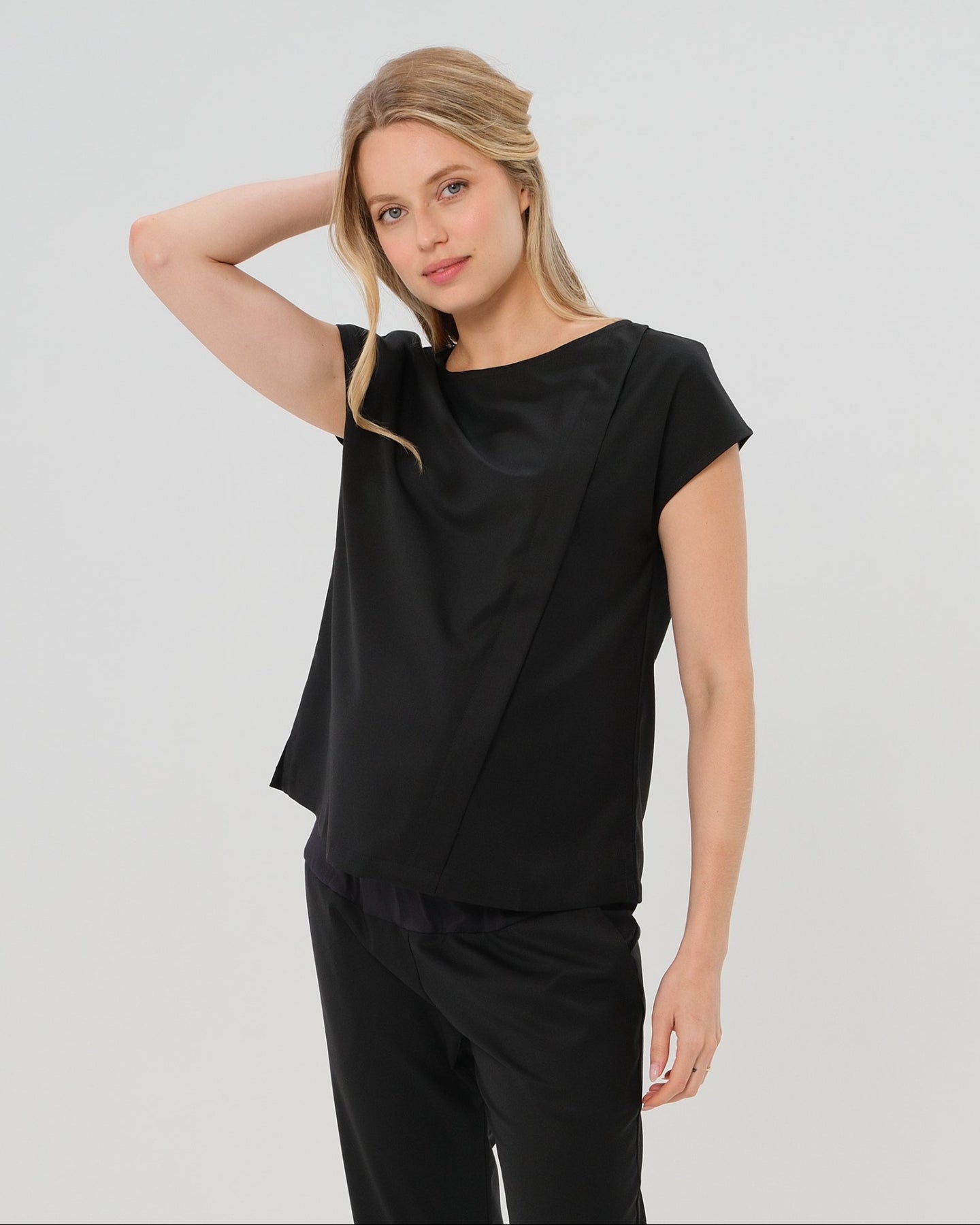 Black short sleeve designer maternity and nursing shell top in breathable tropical wool blend. This best - in - class pregnancy business attire or streetwear style with glowing parent expo reviews is sure to be one of the most sought after designs of 2026. Perfect for work, occasions, outings, and more, the cut is flattering and comfortable, with the diagonal zipper providing the perfect discreet breastfeeding zipper. 