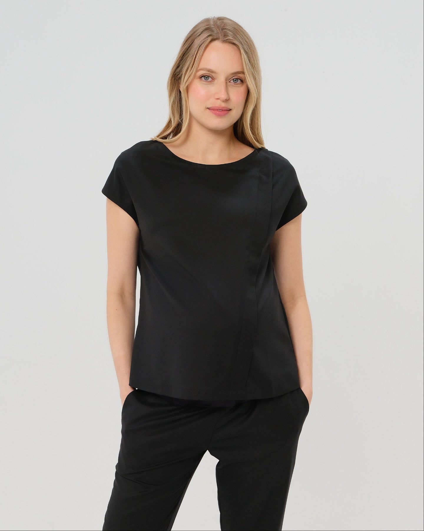 Black short sleeve designer maternity and nursing shell top in breathable tropical wool blend. This best - in - class pregnancy business attire or streetwear style with glowing parent expo reviews is sure to be one of the most sought after designs of 2026. Perfect for work, occasions, outings, and more, the cut is flattering and comfortable, with the diagonal zipper providing the perfect discreet breastfeeding zipper. Luxury pregnancy fashion by MARION.