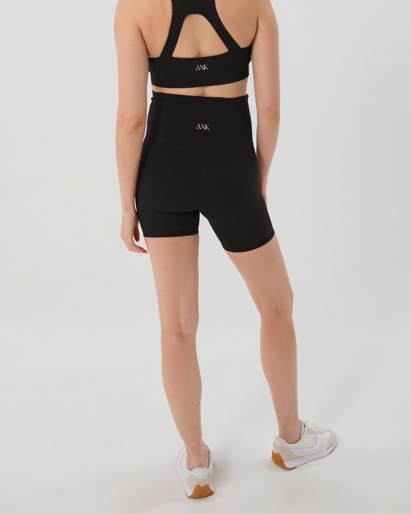 Pregnant woman wearing premium black maternity bike shorts with a supportive high waist and matching high-impact, racerback maternity and nursing sports bra. Best reviewed 2026 premium maternity athletic and activewear by AXK, petite and tall friendly, in regular and plus size options.
