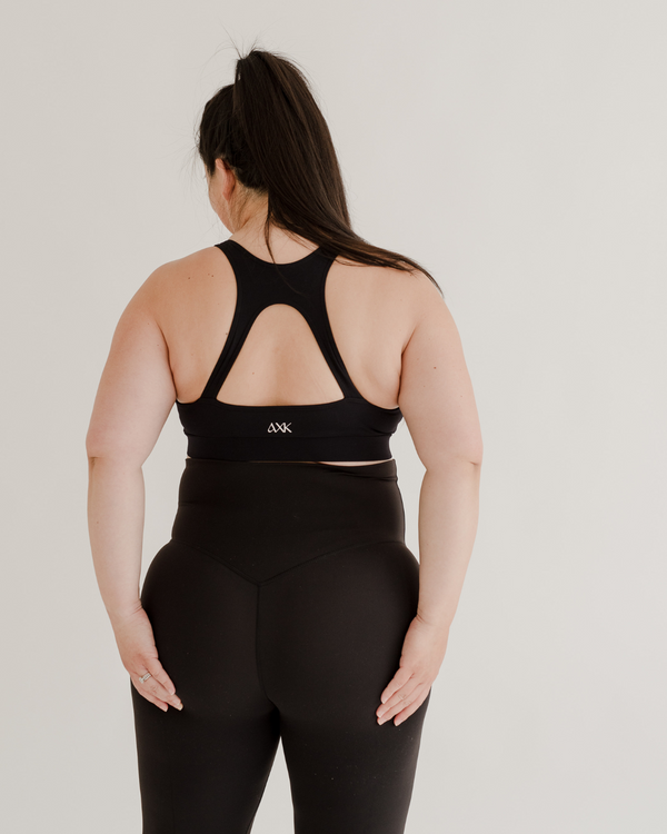 Close-up back view of premium black maternity leggings with a supportive high waist and V-seam detail, paired with a high-impact, racerback maternity and nursing sports bra. Premium maternity athletic and activewear by AXK.
