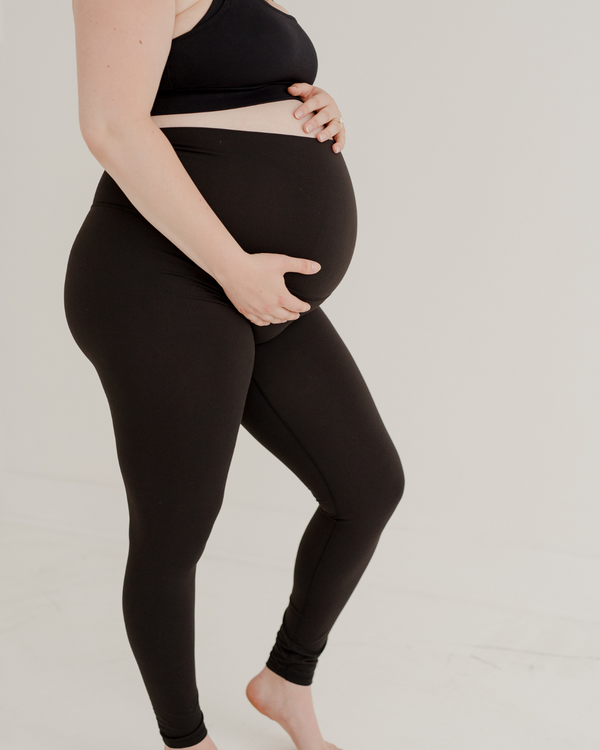 Close-up side view of premium black maternity leggings with a supportive high waist and V-seam detail, paired with a high-impact, racerback maternity and nursing sports bra. Premium maternity athletic and activewear by AXK.