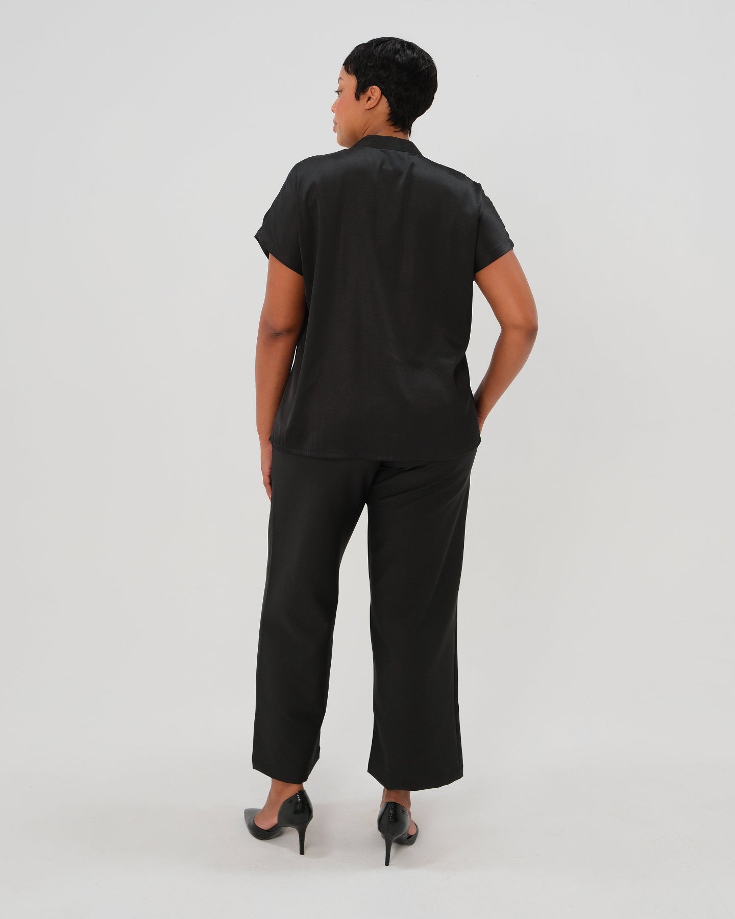 Plus size pregnant model wearing black maternity wide leg dress pants for work with over belly band, boasting glowing 5-star customer reviews. Our best selling sustainable pregnancy business trousers for 2026 are cut with luxury sustainable Italian suiting fabric. These pants are perfect separates paired with our Nathalie blazer for a stylish pant suit, or worn with our viral satin shell top for business casual style. Available in petite, regular, and plus sizes. 