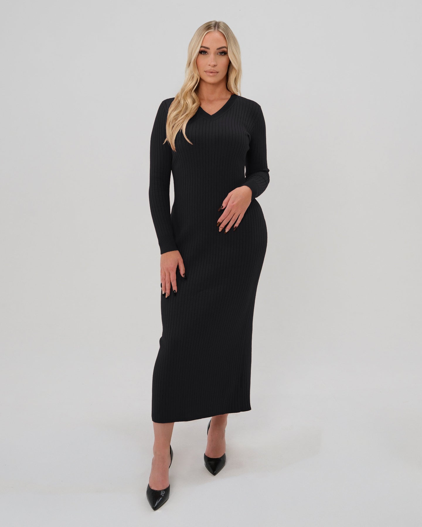 Woman wearing a high-end black long sleeve maxi sweater dress with flattering v neck by MARION. Luxury high stretch cotton knit fabric. Our best reviewed dress for holidays, parties, wedding guest outfits, and fall and winter weather comfort. 