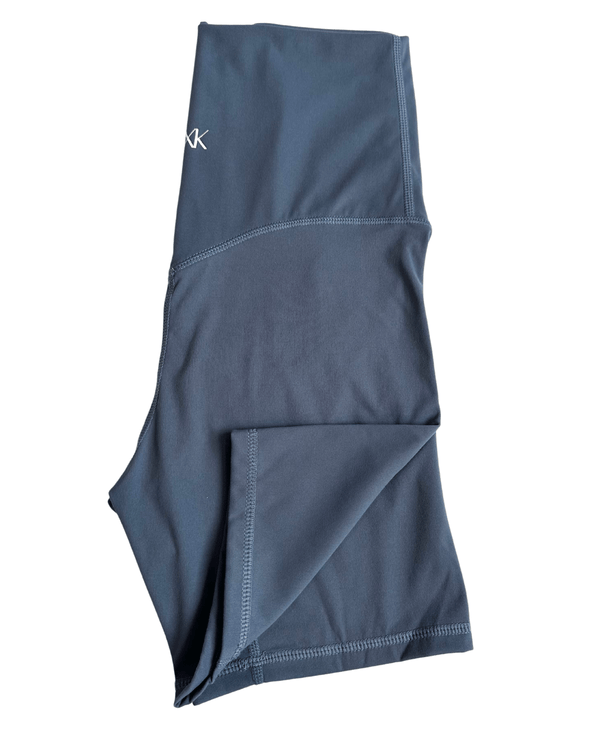 Flat lay of premium blue maternity bike shorts with a supportive high waist and AXK logo detail, displayed on a white background. Premium maternity athletic and activewear by AXK.