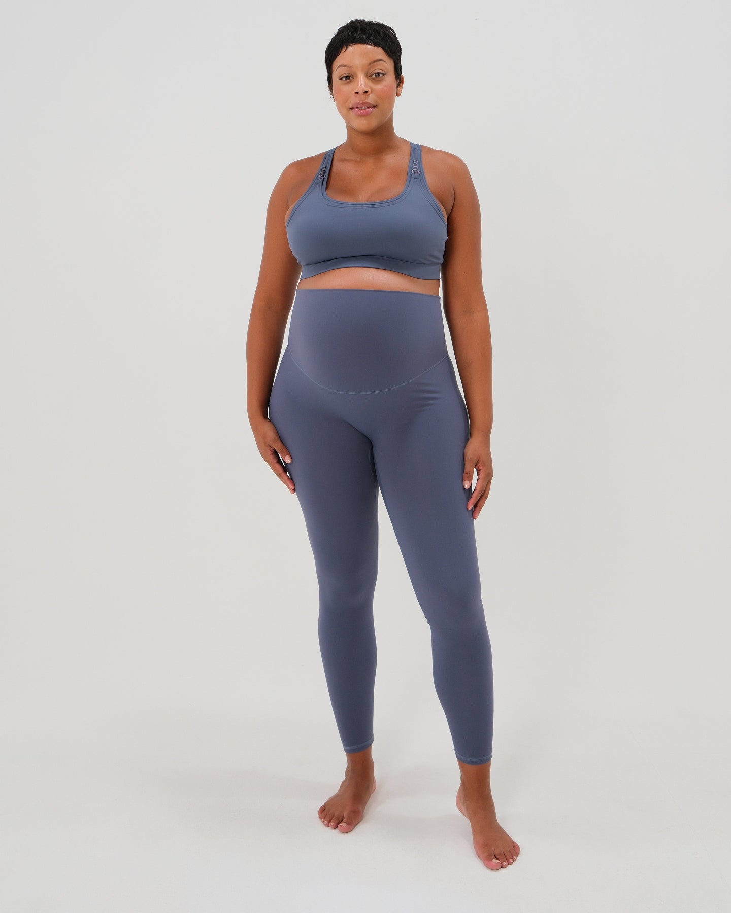 Pregnant plus size model wearing premium blue AXK maternity leggings with a supportive high waist, bum flattering back v seam, seamless front design, and butter soft stretch fabric. Best selling with glowing 5-star reviews, these leggings are perfect for running, pregnancy yoga, walking, biking, or loungewear. High quality 2026 maternity athletic and activewear in regular and plus sizes. Petite and tall friendly. 
