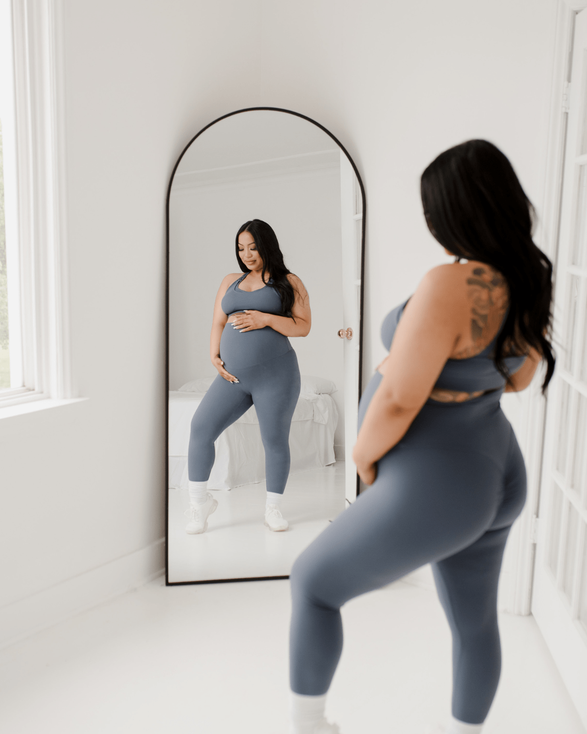 Pregnant woman wearing premium blue maternity leggings with a flattering scrunch butt and matching high-impact, racerback nursing sports bra, standing against a white background. Premium maternity athletic and activewear by AXK.
