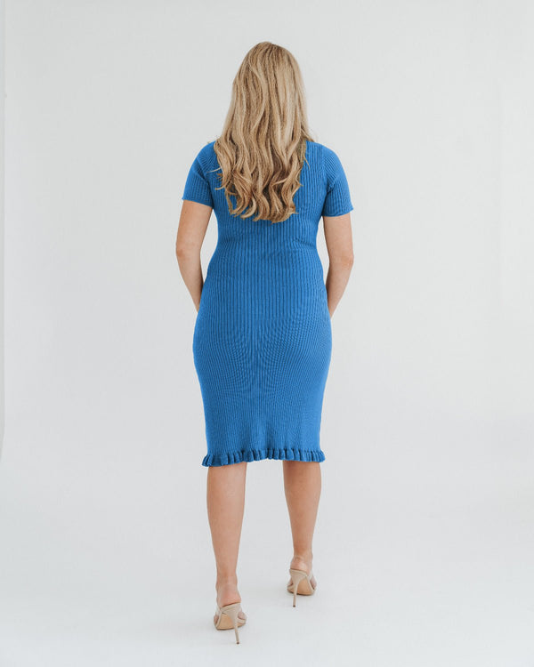 Pregnant woman wearing a luxury knee-length knit maternity dress by MARION, which features breathable stretch cotton knit, a feminine hem ruffle, and easy crew neck. Petite and tall friendly, offered in standard and plus sizes up to 2x. 