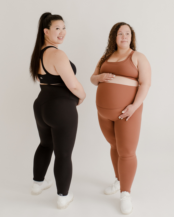 Two women wearing premium maternity leggings with supportive high waists and matching high-impact racerback maternity and nursing sports bras in black and brown, standing against a white background. Premium maternity athletic and activewear by AXK.