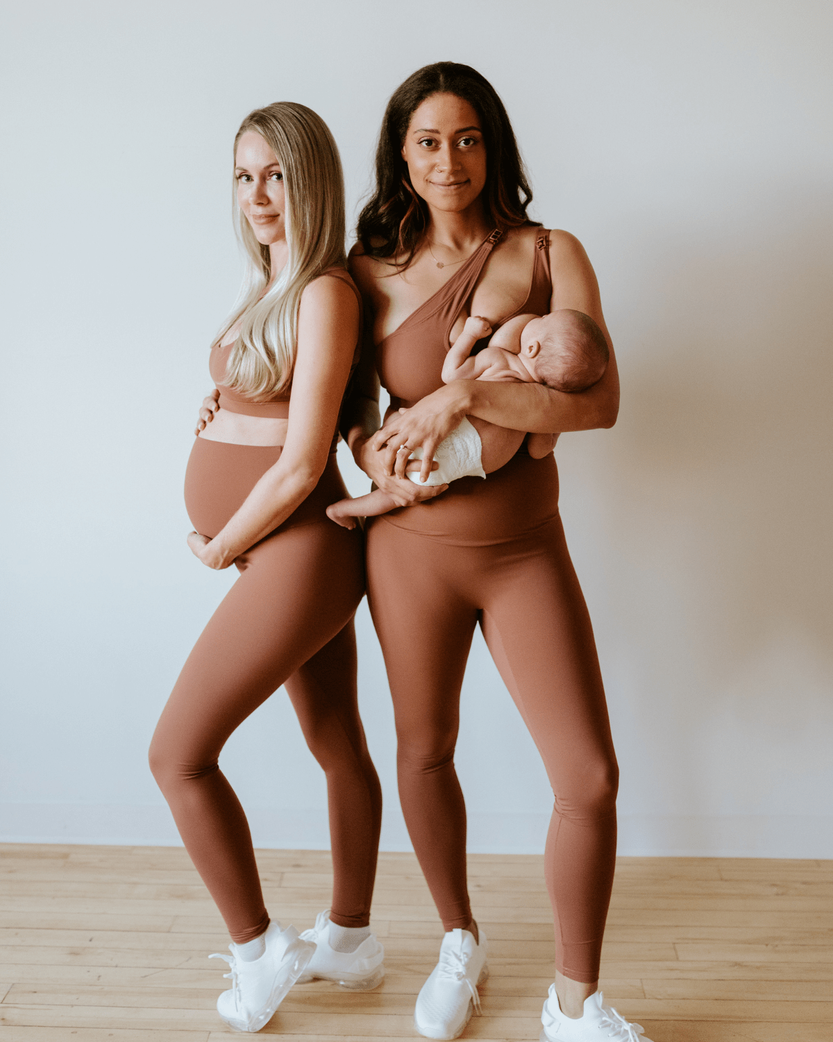 Two pregnant women wearing premium brown maternity leggings with a flattering scrunch butt and matching high-impact, racerback nursing sports bras, standing against a white background. Premium maternity athletic and activewear by AXK - tall, petite, and plus size friendly.