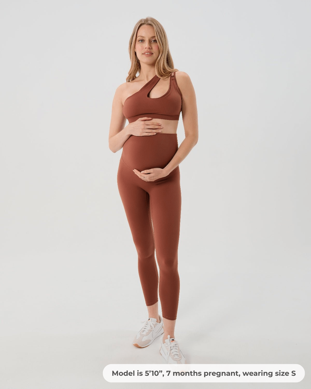 Pregnant woman wearing premium brown maternity leggings with a flattering scrunch butt and matching high-impact, racerback nursing sports bra, standing against a white background. Premium maternity athletic and activewear by AXK - tall, petite, and plus size friendly.