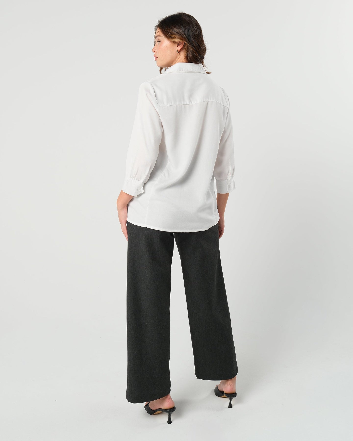 Pregnant model wearing charcoal gray maternity wide leg dress pants for work with over belly band, boasting glowing 5-star customer reviews. Our best selling sustainable pregnancy business trousers for 2026 are cut with luxury sustainable Italian suiting fabric. These pants are perfect separates paired with our Nathalie blazer for a stylish pant suit, or worn with our viral satin shell top for business casual style. Available in petite, regular, and plus sizes. 