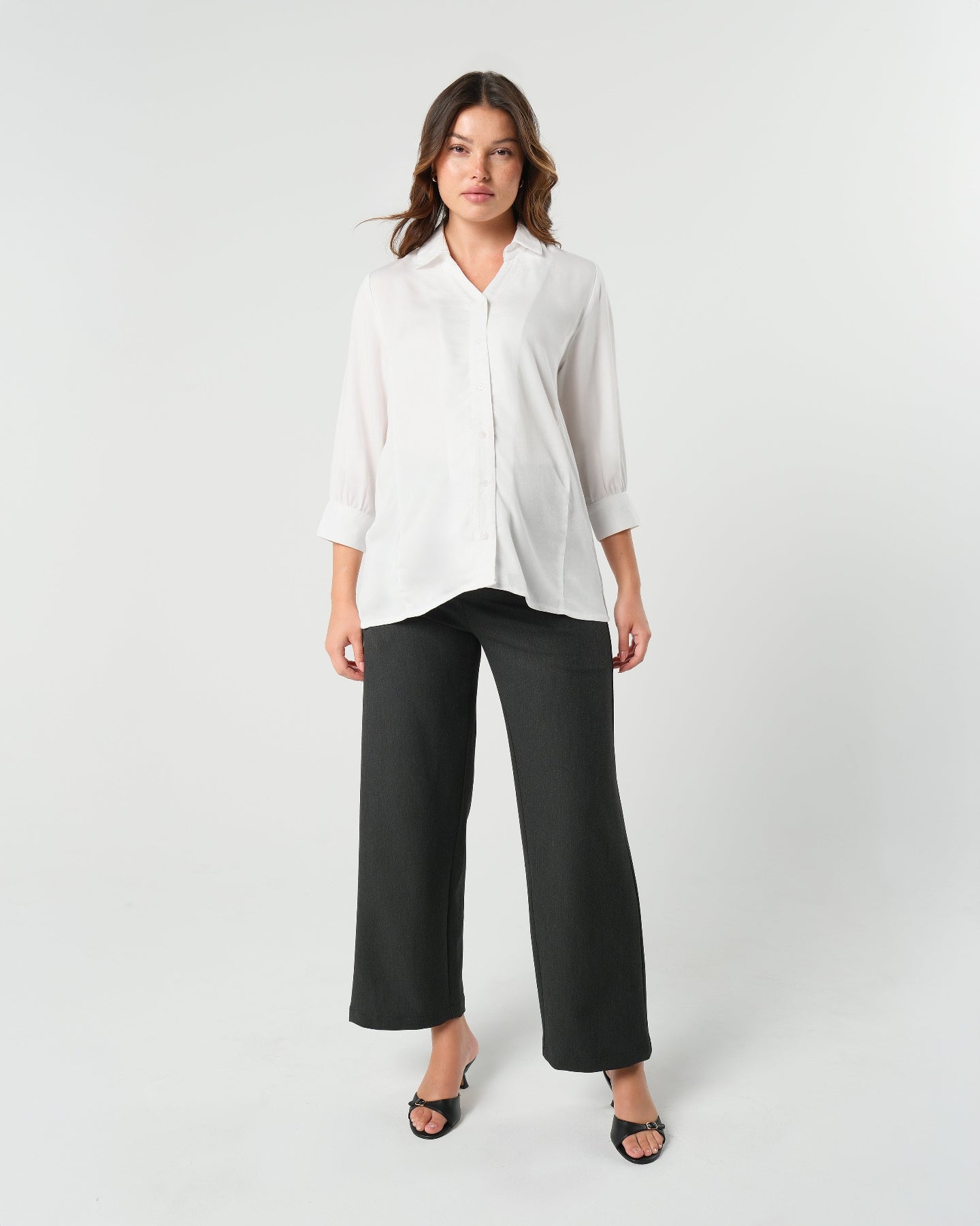 Pregnant model wearing charcoal gray maternity wide leg dress pants for work with over belly band, boasting glowing 5-star customer reviews. Our best selling sustainable pregnancy business trousers for 2026 are cut with luxury sustainable Italian suiting fabric. These pants are perfect separates paired with our Nathalie blazer for a stylish pant suit, or worn with our viral satin shell top for business casual style. Available in petite, regular, and plus sizes. 