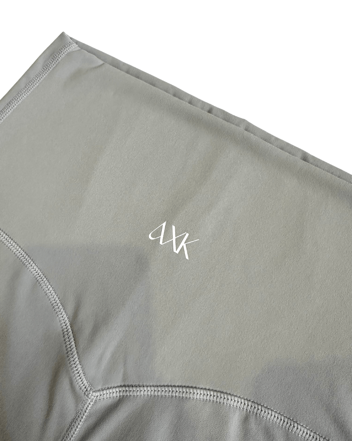 Close-up of premium light grey maternity leggings featuring the AXK logo and flattering V-seam detail, displayed on a white background. Premium maternity athletic and activewear by AXK.
