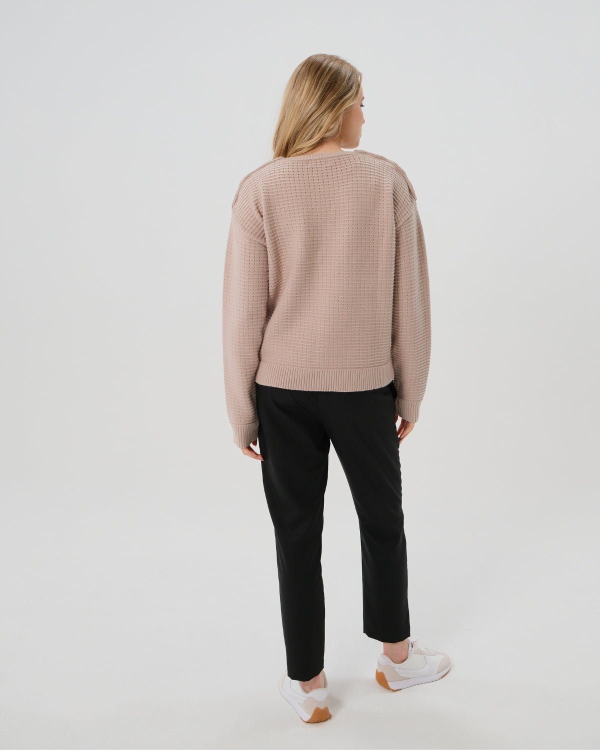 Taupe neutral premium maternity and nursing sweater in stretch cotton box knit. Featuring shoulder button detail for breastfeeding and discreet hem thumbholes for an extra cozy fit. Oversized fit is flattering, polished, and versatile - transitioning from pregnancy workwear to loungewear to streetwear with ease. Petite and tall friendly; available in regular and plus size. Back view.