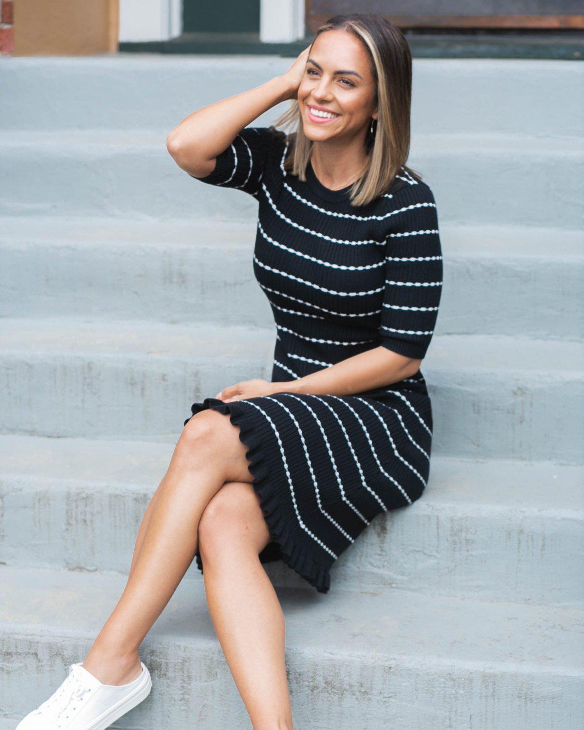Striped knit maternity and nursing dress in black and white. Knee length three quarter sleeves with feminine hem detail. Ideal for maternity business workwear, date, church, wedding guest, brunch, and occasion. MARION luxury maternity workwear. Worn by a petite 5&#39;2&quot;, postpartum model in this image. 