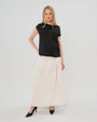 Pregnant woman wearing a modest off-white cream pleated designer maternity maxi maternity skirt in luxurious TENCEL satin by MARION. This luxury skirt can be worn over or under your belly bump. It fastens with a zip, and features deep functional pockets and a flexible elastic waistband for comfort. This refined, timeless style epitomizes quiet luxury. Perfect for maternity work wear, wedding guest dress, occasion wear, pregnancy street style, and baby shower outfits. Petite and tall friendly.