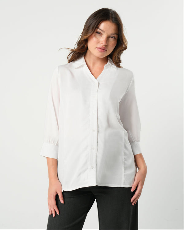 White maternity button down shirt for pregnancy and nursing by MARION. Maternity workwear top with no gap technology that prevents your bra from showing. Cut with luxury sustainable TENCEL, this classic blouse is ideal for a business meeting at the office, the courtroom, or Saturday errands and brunch. Available in petite and regular sizes, and made for pregnancy, nursing, postpartum, and mama life. 