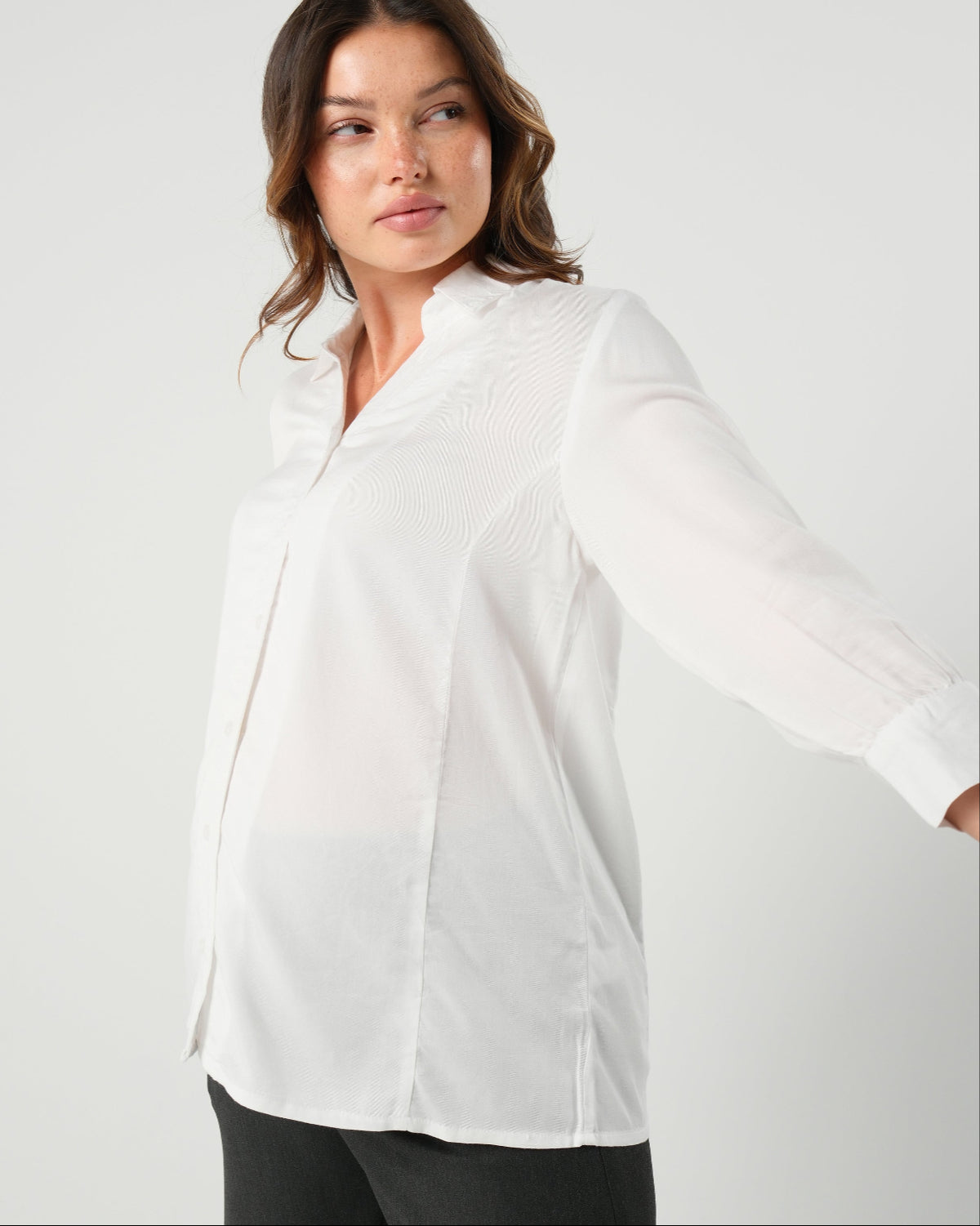 White maternity button down shirt for pregnancy and nursing by MARION. Maternity workwear top with no gap technology that prevents your bra from showing. Cut with luxury sustainable TENCEL, this classic blouse is ideal for a business meeting at the office, the courtroom, or Saturday errands and brunch. Available in petite and regular sizes, and made for pregnancy, nursing, postpartum, and mama life. 