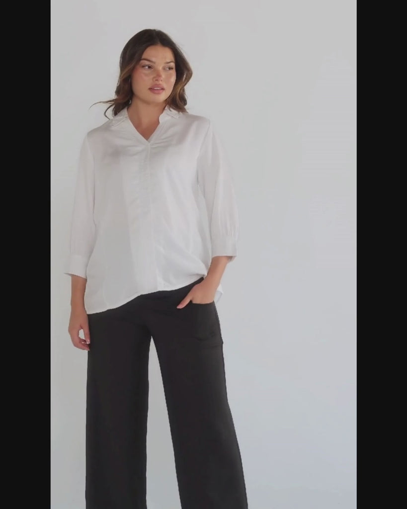 White maternity button down shirt for pregnancy and nursing by MARION. Maternity workwear top with no gap technology that prevents your bra from showing. Cut with luxury sustainable TENCEL, this classic blouse is ideal for a business meeting at the office, the courtroom, or Saturday errands and brunch. Available in petite and regular sizes, and made for pregnancy, nursing, postpartum, and mama life. 