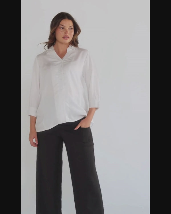 White maternity button down shirt for pregnancy and nursing by MARION. Maternity workwear top with no gap technology that prevents your bra from showing. Cut with luxury sustainable TENCEL, this classic blouse is ideal for a business meeting at the office, the courtroom, or Saturday errands and brunch. Available in petite and regular sizes, and made for pregnancy, nursing, postpartum, and mama life. 